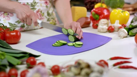 Woman cuts cucumber with sharp knife on chopping board Stock Footage 230039313