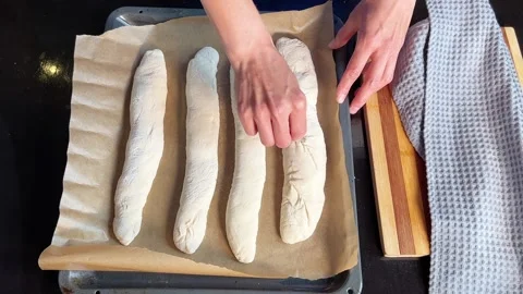 Woman cuts patterns on raw bread rolls. Woman is prepearing dough for baking Stock Footage 295187860