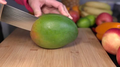 Woman is cutting amango in half on a cutting board. Stock Footage 344866498