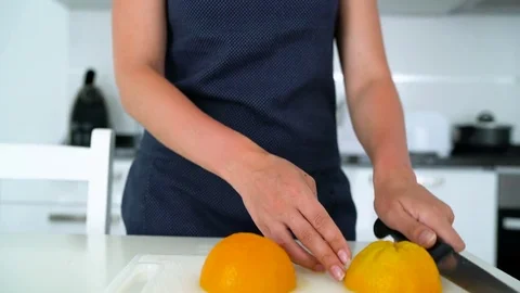 Woman cutting and eating orange in a modern kitchen Stock Footage