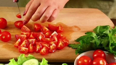 A woman is cutting cherry tomatoes to make a vegetable salad. Close-up Stock Footage