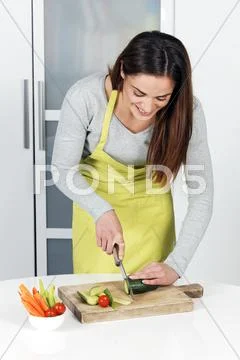 Woman cutting cucumber Stock Photos