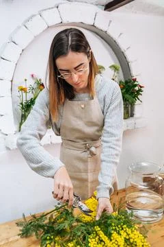 Woman cutting flowers stems and putting into vase Stock Photos