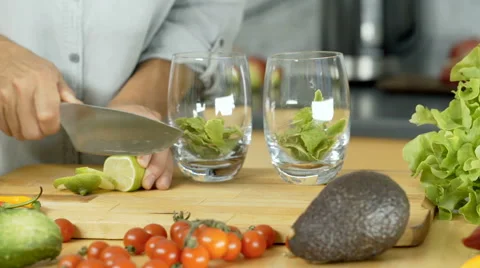 Woman cutting lime into slices and adding it into glasses, dolly shot Stock Footage