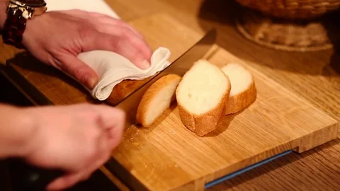 A woman cutting a loaf of bread with a bread knife. Stock Footage 77225551