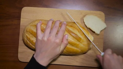 A woman cutting a loaf of bread with a bread knife. Stock Footage 82379691