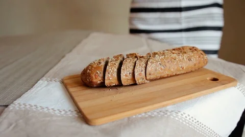 A woman cutting a loaf of bread with a bread knife Stock Footage 105884766