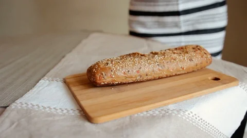 A woman cutting a loaf of bread with a bread knife Stock Footage 105884768