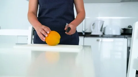 Woman cutting orange in a modern kitchen Stock Footage
