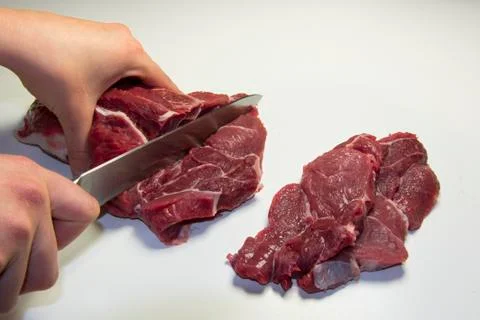 Woman cutting raw equino meat Stock Photos