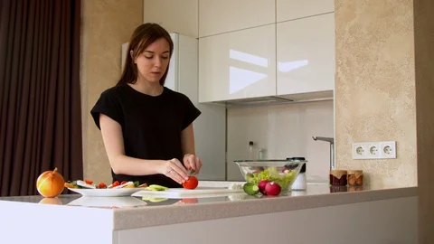 Woman cutting tomatoes in kitchen Stock Footage 130062306