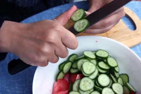 Woman cutting vegetables while preparing a salad in the kitchen Stock Photos