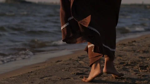 Woman dancing against the backdrop of the sunset sea. skirt close up, cloth in Vidéo 104078536