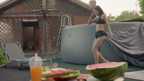 Woman Dancing Energetically in Backyard with Pool Watermelon and Juicy Drink Stock Footage 345974116