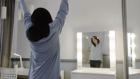 Woman dancing with hands raised gesturing victory rear view bedroom scene Stock Footage 320936067