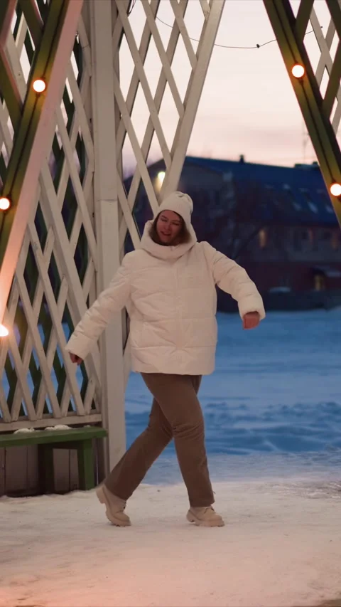 Woman Dancing Joyfully Under Winter Arch With String Lights In Outdoor Evening Stock Footage 346794777