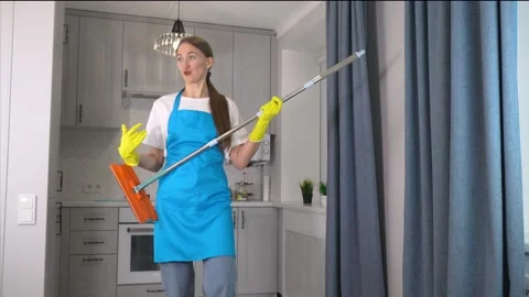 Woman dancing in kitchen. She pretends playing on guitar. holds mop in his hands Vídeo Stock 231329920