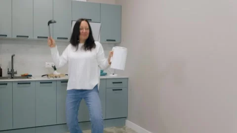 Woman dancing in kitchen using kitchenware as musical instruments Stock Footage 304983362