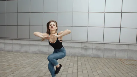 Woman dancing performs modern hip-hop dance posing, freestyle in street, urban Stock Footage 97698791