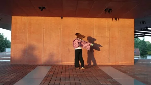 Woman dancing in sunset light with dramatic shadow on textured wall Stock Footage 345029191