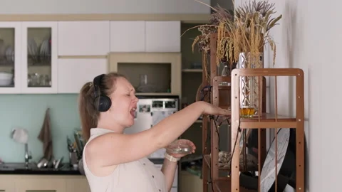 Woman dancing while cleaning her apartment. Stock Footage 308443623