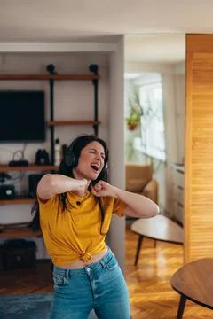 Woman dancing while listening a music on a headphones at home Stock Photos