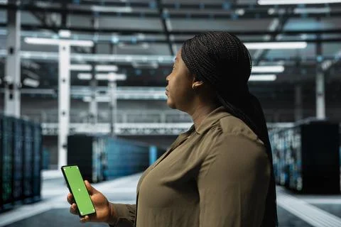 Woman in data center checking mainframes performance data on mockup smartphone Foto stock