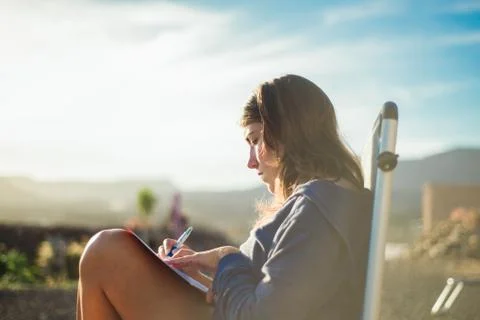 Woman on deckchair writing in journal, Corralejo, Fuerteventura, Canary Islands Stock Photos