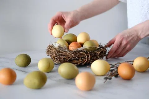 A woman decorates the table with Easter eggs in a decorative nest of twigs Foto stock