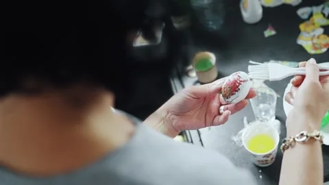 Woman decorating an Easter egg with detailed and colorful patterns Stock Footage 304353517