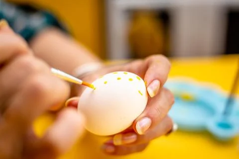 Woman decorating a easter eggs with dots. Stock Photos