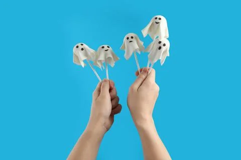 Woman with delicious ghost shaped cake pops on light blue background, closeup Stock Photos