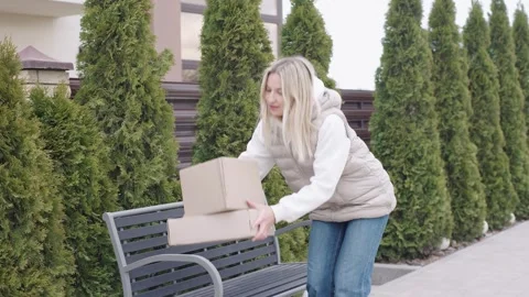 Woman delivers packages while walking along a pathway lined with trees Video stock 316596704
