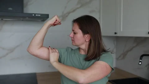 Woman Demonstrating Basic Arm Workout Routine in Modern Kitchen Setting Video stock 273287659