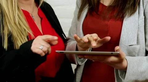 Woman demonstrating &amp; using ipad tablet app to other lady smart business clothes Stock Footage 47817760
