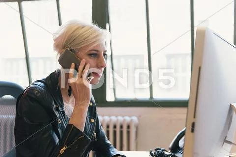 Woman At Desk Using Smartphone To Make Telephone Call