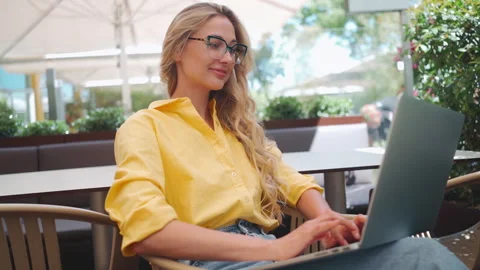 Woman developer coding on laptop at outdoor restaurant Stock Footage 274548346