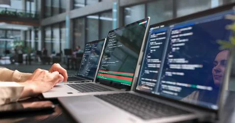 Woman Developer Compares Code Changes On Laptop Using Visual Merge Tool. Stock Photos