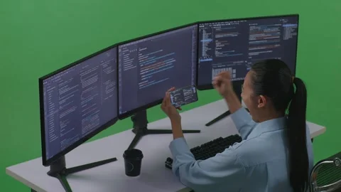 Woman Developer Looking At Code On Mobile Phone While Write Code With Multiple Stock Footage 252578036