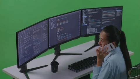 Woman Developer Talking On Mobile Phone While Write Code With Multiple Computer Stock Footage 252578148