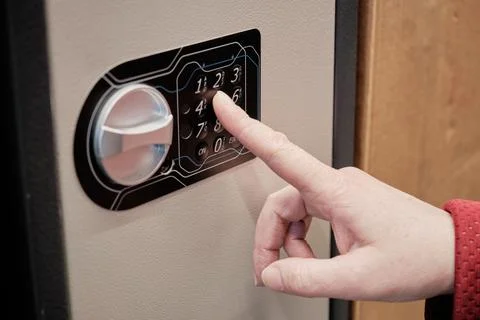 Woman dials a code on an iron safe. Hands close up shot Stock Photos
