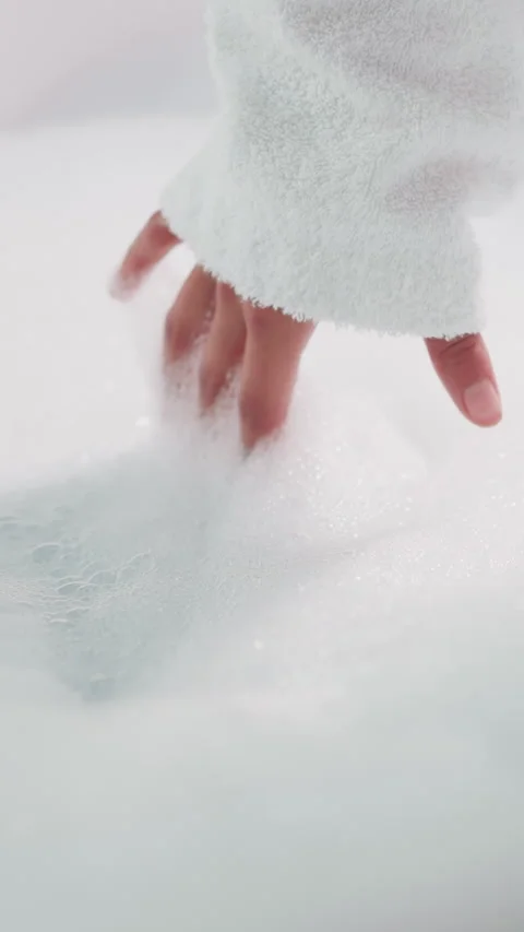 Woman dips fingers into thick bubble bath Stock Footage 309829614