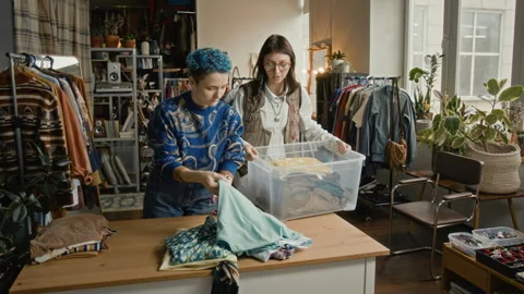 Woman with Disability Checking Secondhand Clothes Before Selling in Thrift Store Stock Footage 328360497