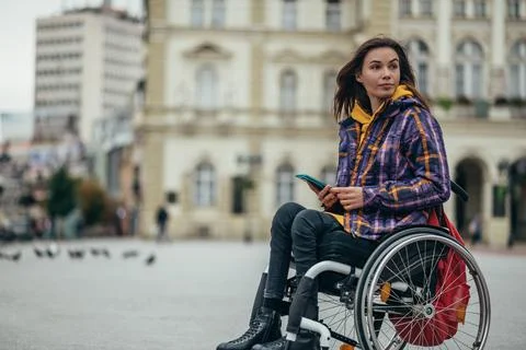 Woman with disability using a smartphone while out in the city Stock Photos