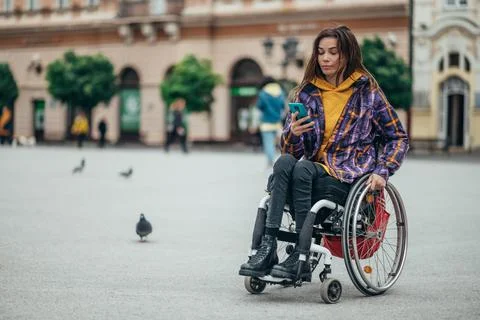 Woman with disability using a smartphone while out in the city Stock Photos