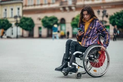 Woman with disability using a smartphone while out in the city Stock Photos