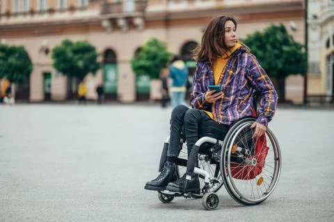 Woman with disability using a smartphone while out in the city Stock Photos