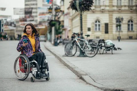 Woman with disability using a smartphone while out in the city Stock Photos