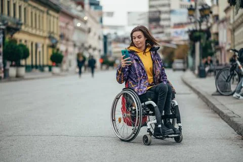 Woman with disability using a smartphone while out in the city Stock Photos