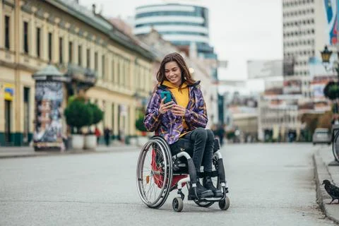 Woman with disability using a smartphone while out in the city Stock Photos